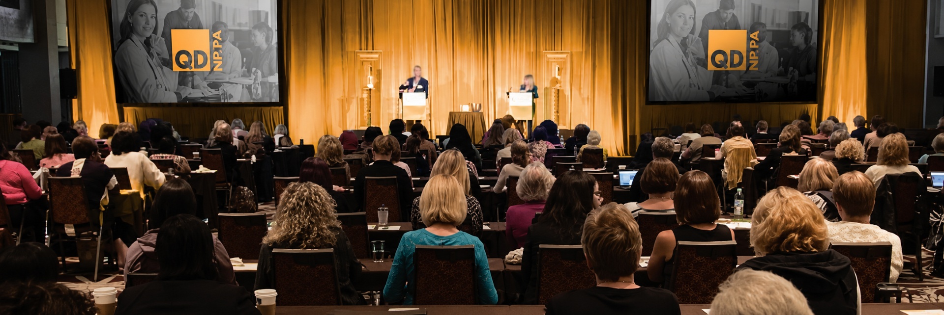 A packed room at a QD NP/PA regional conference, with faculty presenting on stage